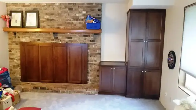 Custom cherry entertainment center built into a brick fireplace wall with a matching tall cabinet, Portland area
