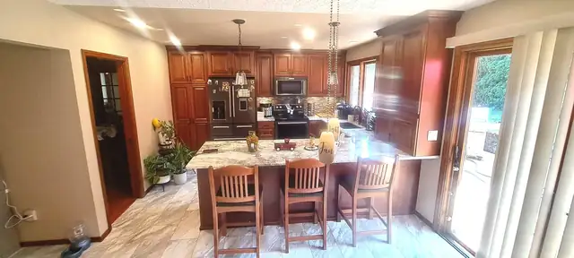 Kitchen with cherry cabinets to the ceiling, granite island seating for three and pendant lights