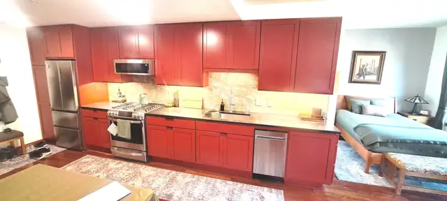 Kitchen with red painted Shaker cabinets, stainless range and stone tile backsplash