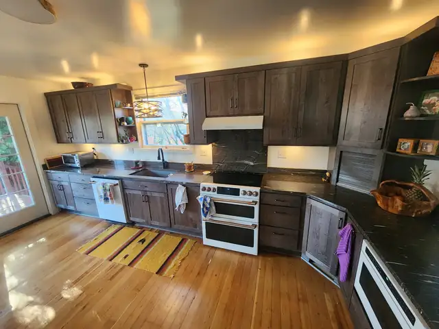 Northeast Portland kitchen with dark stained maple cabinets, black countertops and a white double-oven range