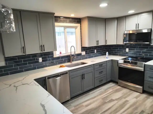Kitchen with gray Shaker cabinets, a navy subway tile backsplash, white marble-look counters and stainless appliances